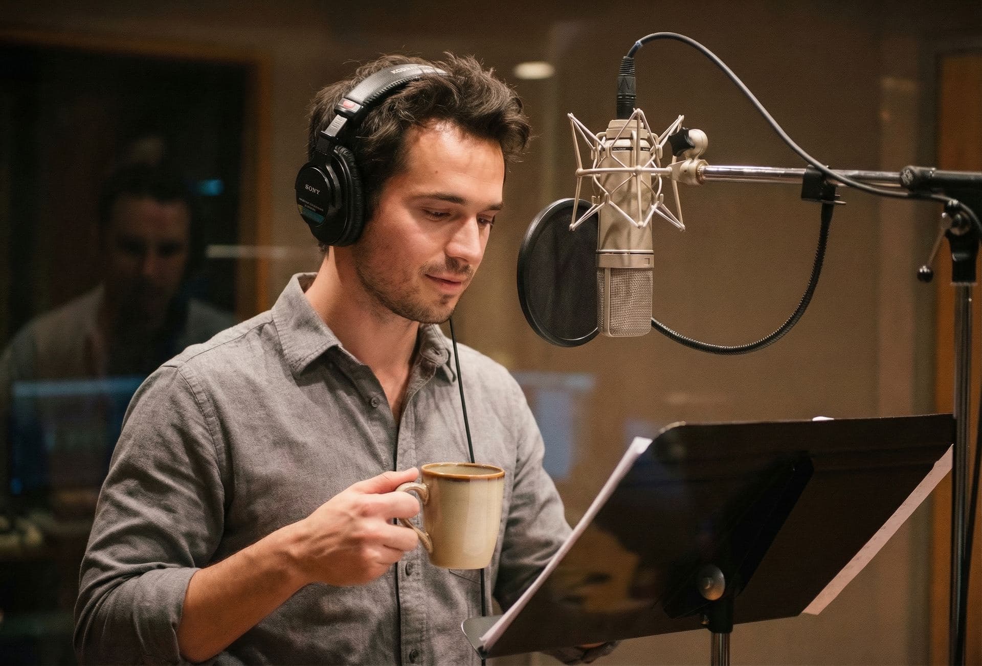 CJ Emerson working at a microphone, headphones on, between takes in the studio